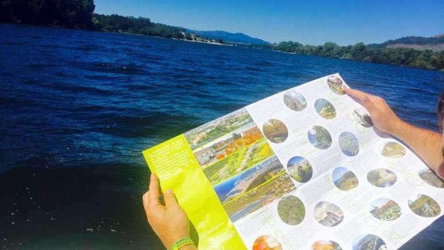 Un turista sostiene uno de los folletos, en el estuario del Miño. // D.P.