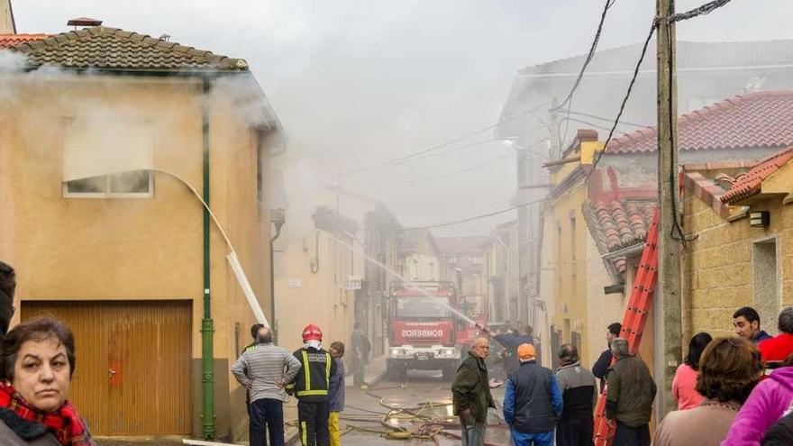 Los vecinos observan el trabajo de los bomberos apagando el fuego.