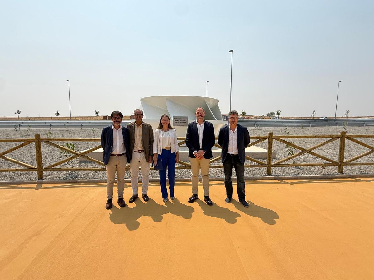 Representantes de la Junta, el Ayuntamiento de Cáceres e Iberdrola posan junto al rodete instalado en una de las rotondas de la Ronda Sur.