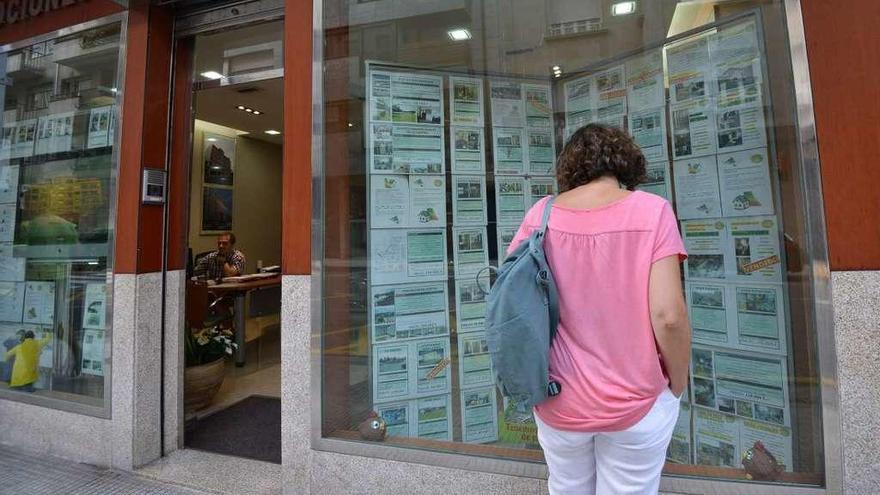 Una mujer observa anuncios de pisos en alquiler en una inmobiliaria.