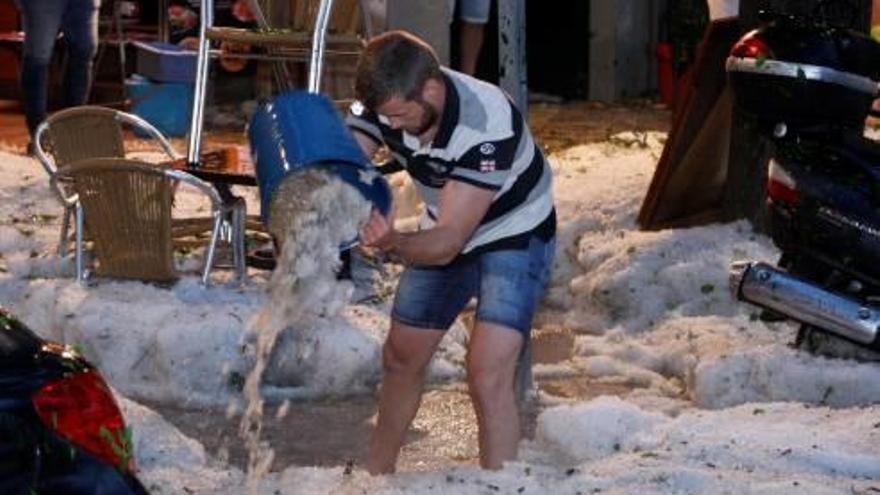 Un home netejant una vorera després del temporal que va afectar Girona, el 30 de juny.