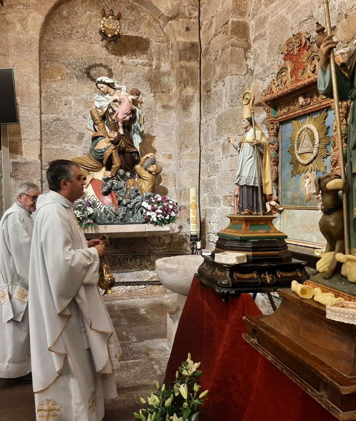 El párroco de Bueu bendice con incienso la talla de San Martiño. |  