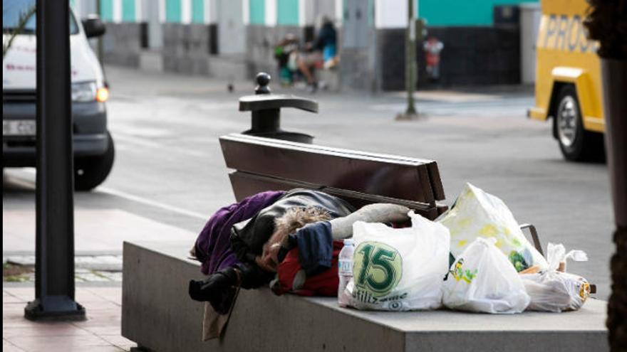 Una persona sin techo duerme en un banco de la zona del parque Santa Catalina.