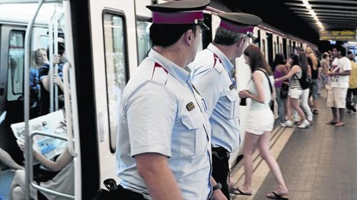 Dos mossos vigilanla entrada a los vagones del metro en busca de carteristas.