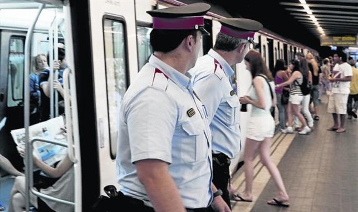 Dos mossos vigilenl’entrada als vagons del metro a la recerca de carteristes.