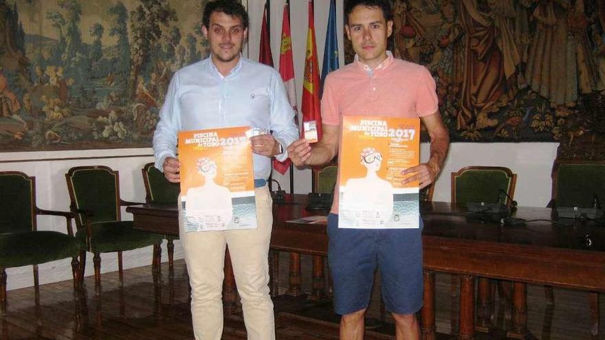 Tomás del Bien (izquierda) y Javier Vega presentan el cartel de actividades de la piscina y el carné.