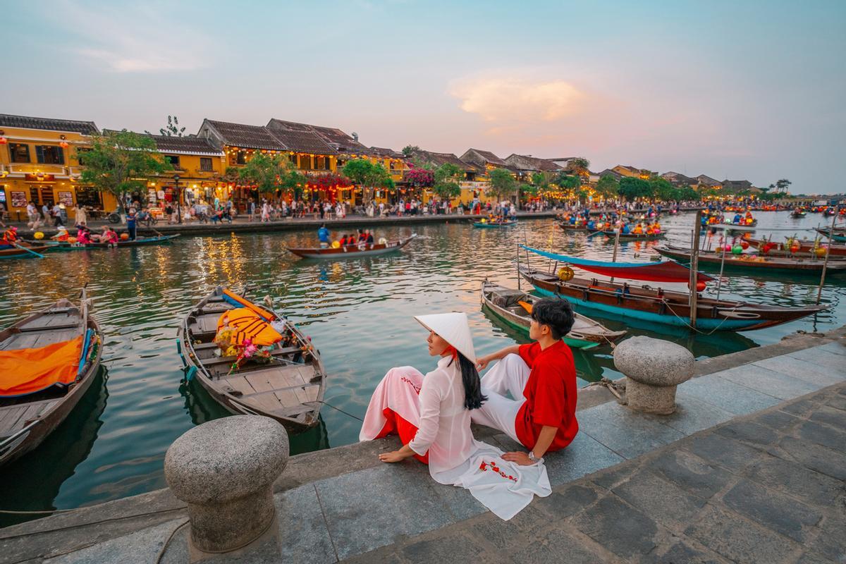 Pareja con vestimenta tradicional vietnamita en la orilla del río Thu Bon