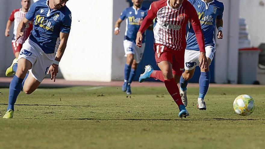 Bertín, del Sporting B, conduce el balón con la oposición de dos defensores del Melilla.