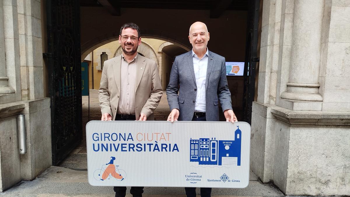 Lluc Salellas i Quim Salvi amb un dels nou cartells de "Girona Ciutat Universitària".