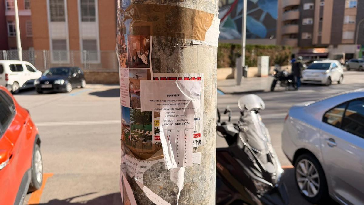 Farola llena de carteles publicitarios en una calle de Cartagena