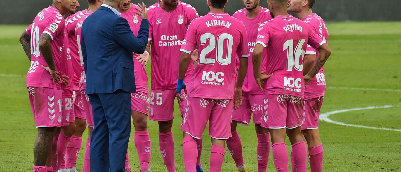 José Mel Pérez gesticula con el brazo derecho, mientras el capitán Aythami Artiles Oliva y Sergio Ruiz conversan ante el plantel de la UD, en el centro del campo, en el descanso del partido ante el Almería.
