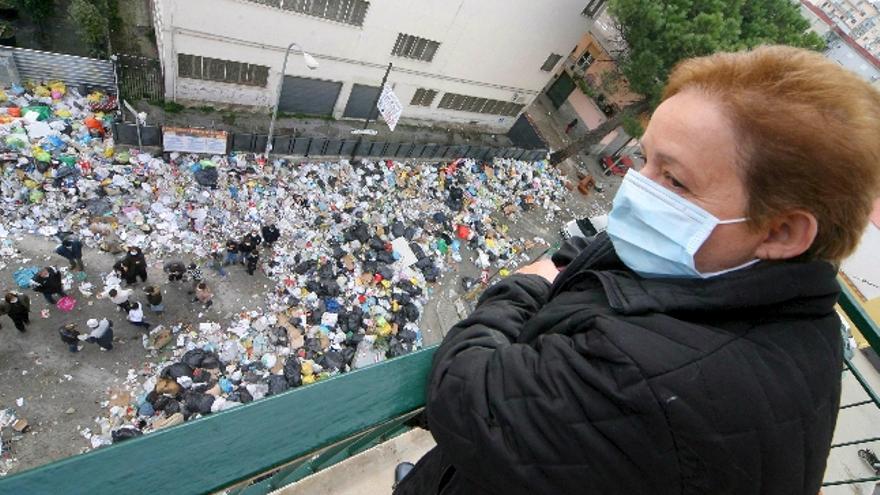 Una mujer cubre su cara con una mascarilla al asomarse desde su balcón a una calle llena de basura en Melito, sur de Italia, hoy, viernes 1 de febrero. Los habitantes de Melito prendieron hoy fuego a toneladas de basura que permanecían en las calles para protestar contra la política regional y nacional, incapaces de resolver la crisis de los vertederos en esta zona de Italia. La Comisión Europea envió ayer un &quot;último aviso&quot; a Italia para que resuelviera los problemas de recogida de basura en la Campania (Sur); y le advirtió de que, de lo contrario, pedirá al Tribunal de Justicia de la UE que les sancione. La denominada &quot;crisis de la basura&quot; se debe a la falta de vertederos y a la implicación de la camorra (la mafia napolitana); en el negocio de la recogida de basuras.