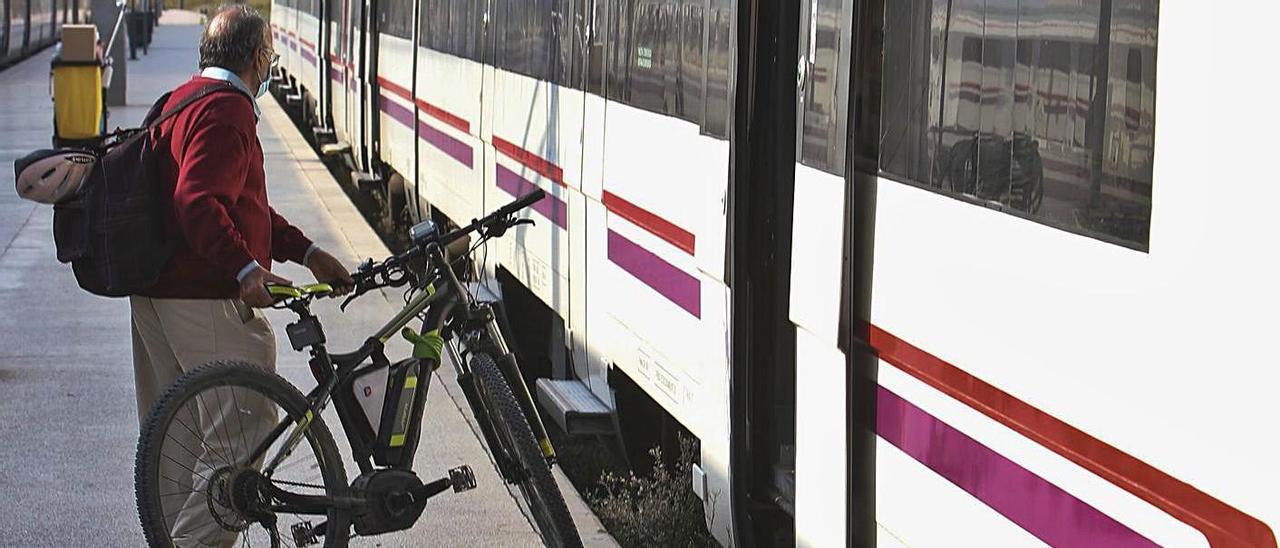 Un pasajero se dispone a subir a un tren de Cercanías con su bicicleta en Alicante.