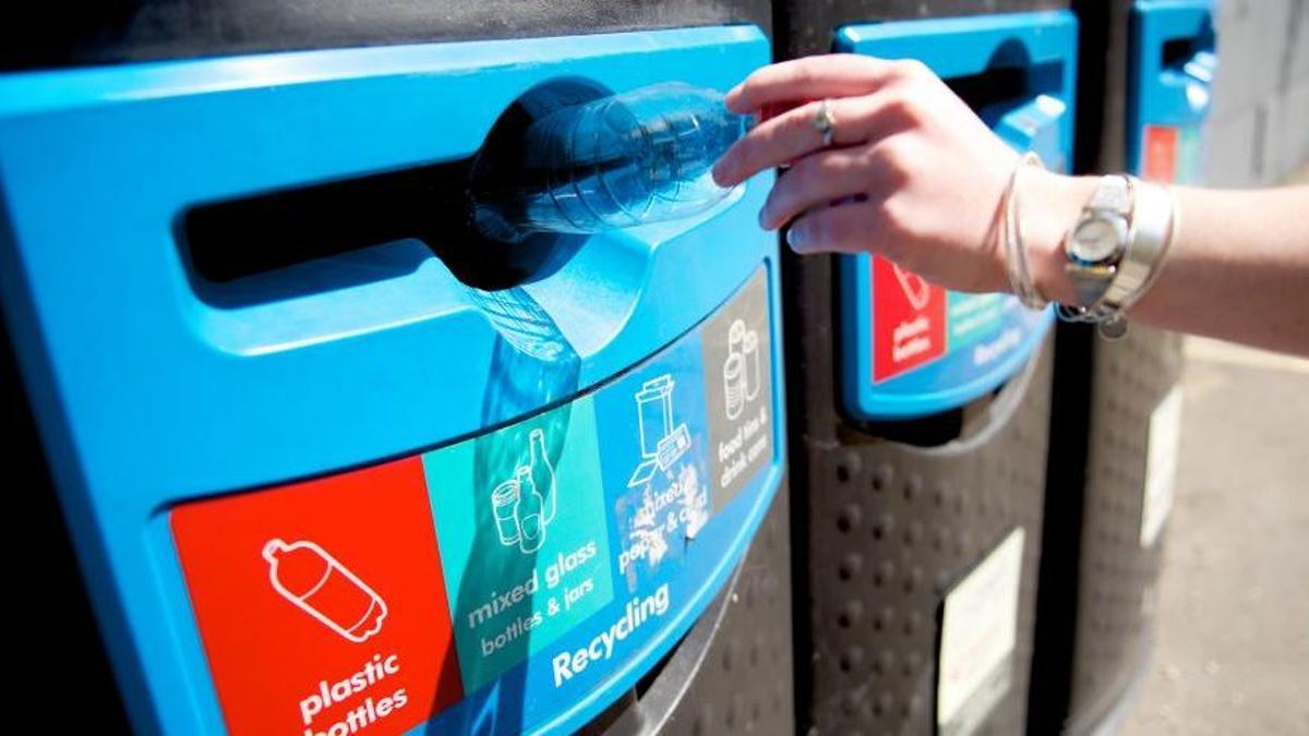 Una personas tira una botella de plástico en un contenedor de Londres.