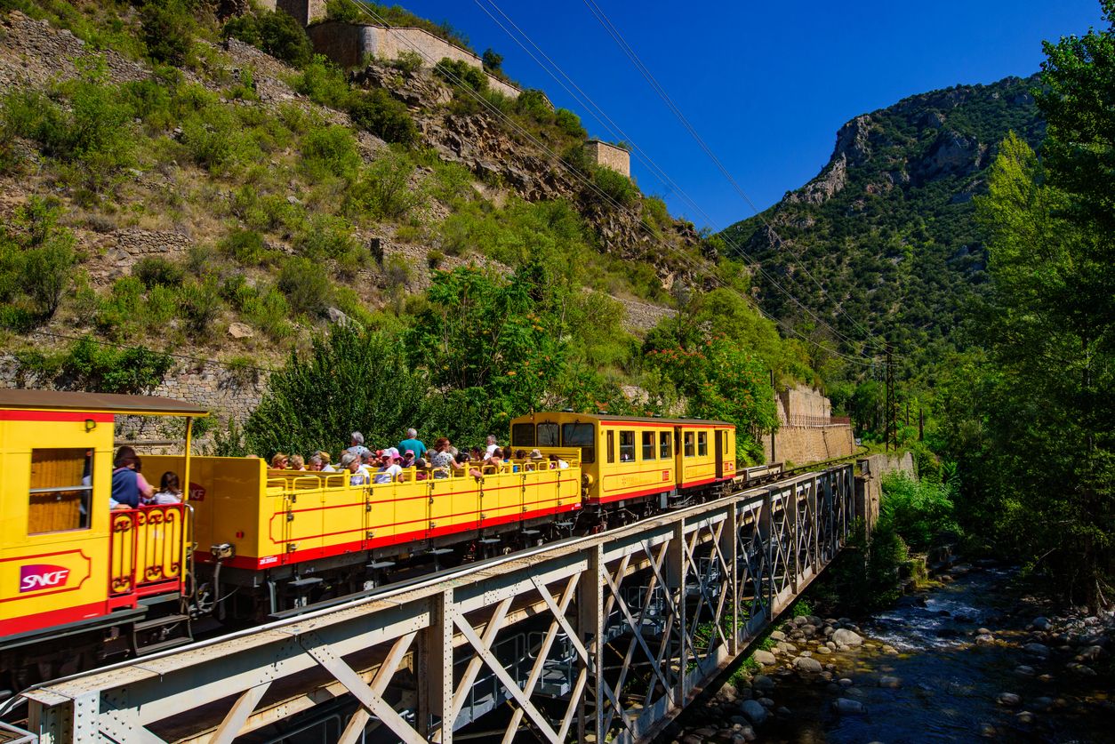 El Pequeño Tren Amarillo (Le Petit Train Jaune) que pasa por Villefranche-de-Conflent, Francia con sus vagones destapados.