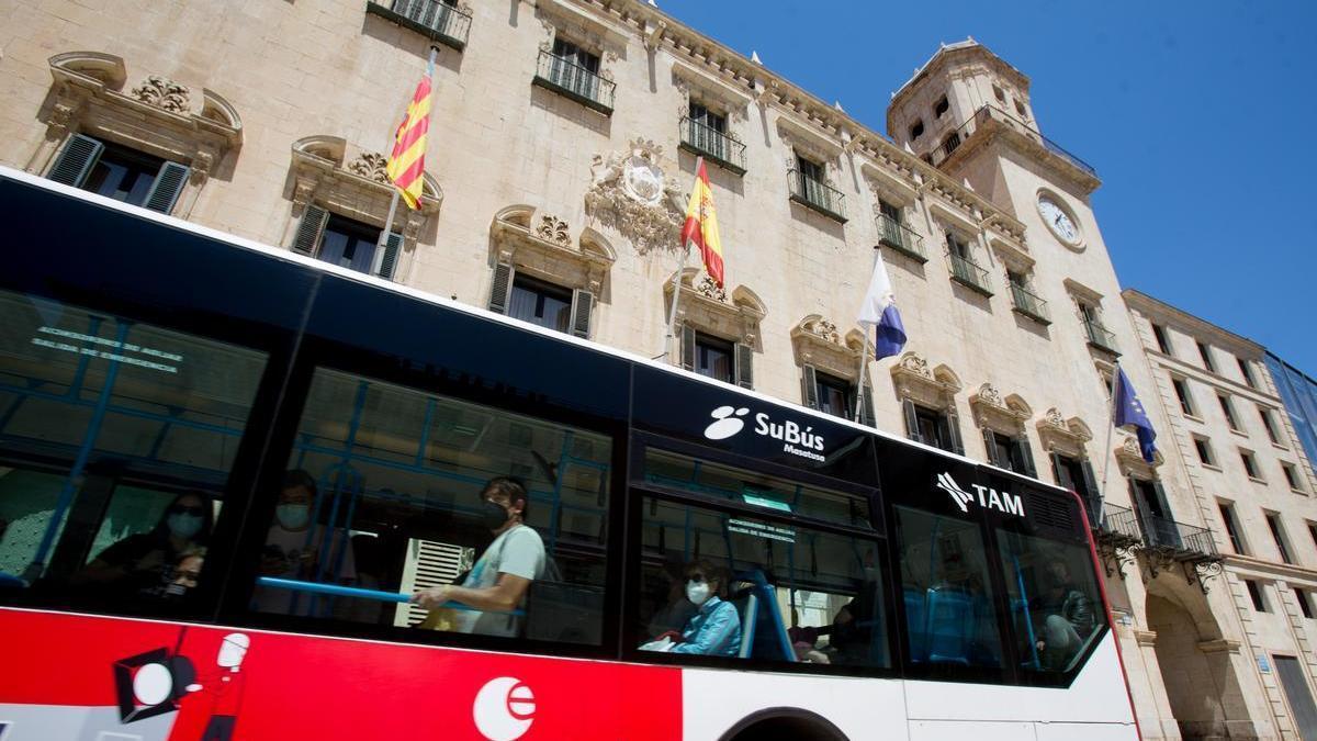 Un autobús del servicio urbano, a su paso por delante del Ayuntamiento de Alicante