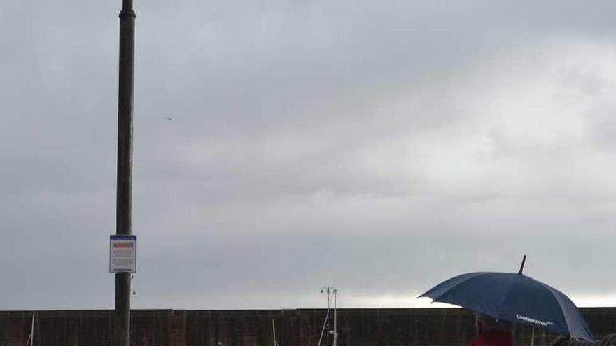 Un vecino pasea por el puerto lastrín bajo la lluvia.