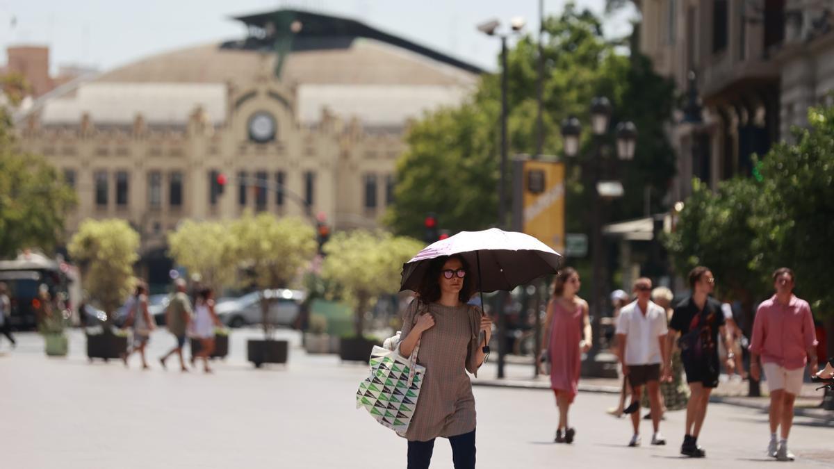 Una mujer se protege del sol con un paraguas en el centro de València.