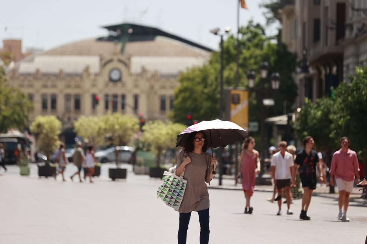 Una mujer se protege del sol con un paraguas en el centro de València.
