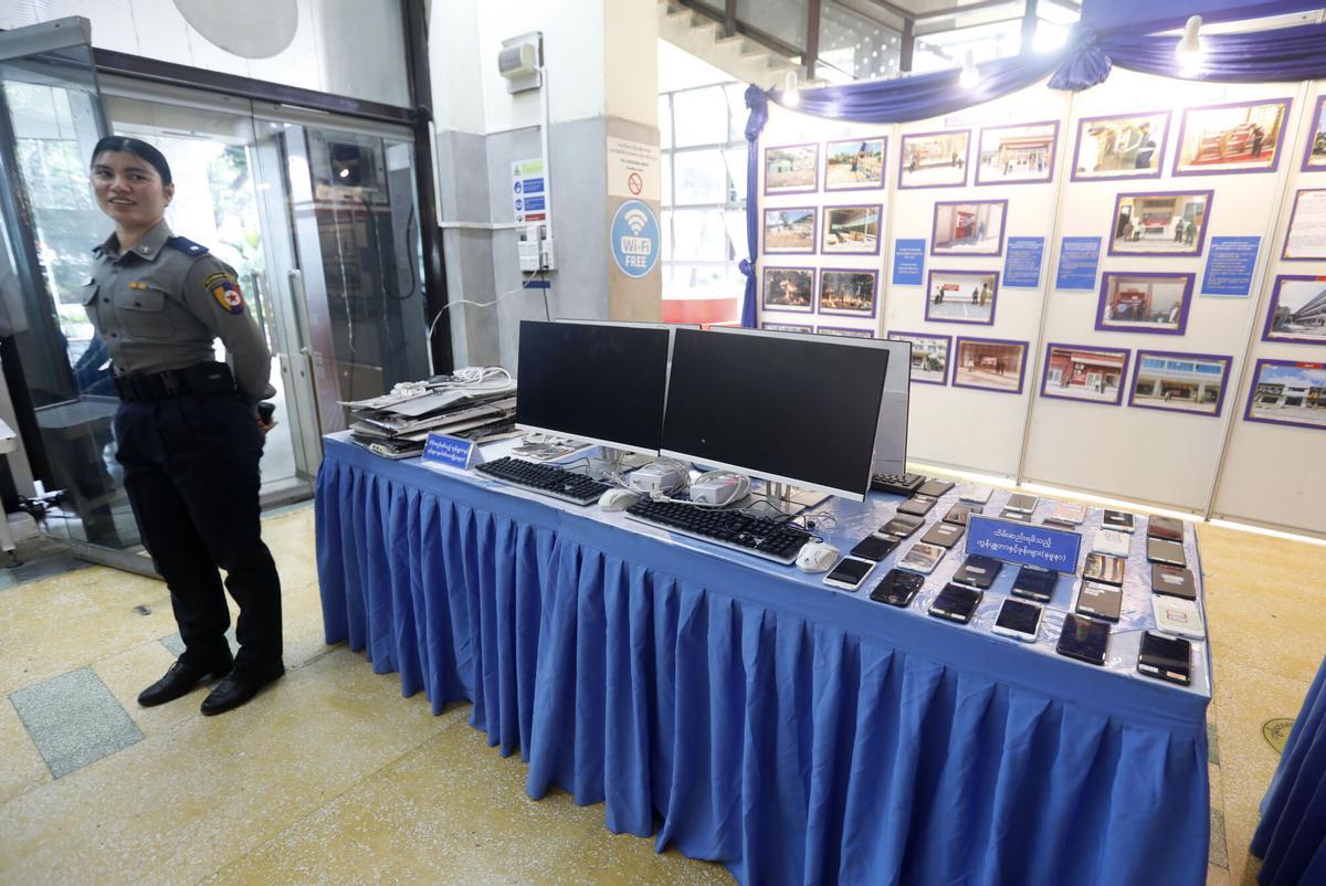 Una agente de policía de Myanmar muestra teléfonos móviles y ordenadores intervenidos a una red de estafadores por internet, el pasado diciembre.