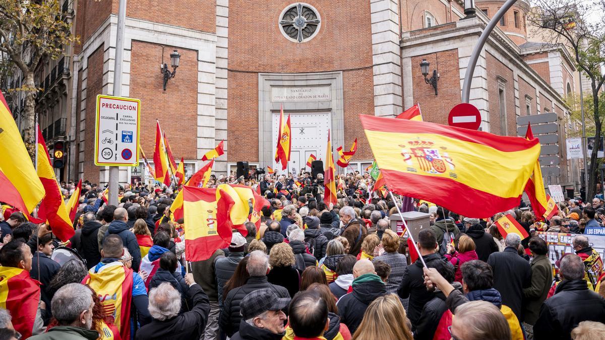 Varias personas con banderas de España durante una concentración frente a las sede del PSOE de la calle Ferraz, a 6 de diciembre de 2023, en Madrid (España).