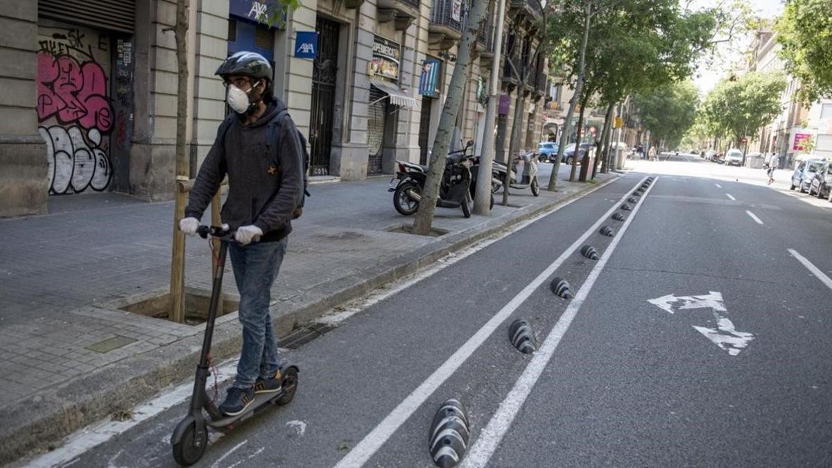 Un hombre circula en patinete por Consell de Cent, en Barcelona.