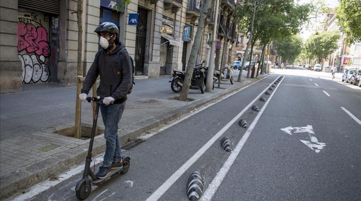 Un hombre circula en patinete por la calle de Consell de Cent, en Barcelona.