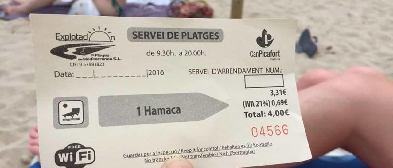 Una turista exhibe el billete por el alquiler de los servicios playeros en Can Picafort, este año.