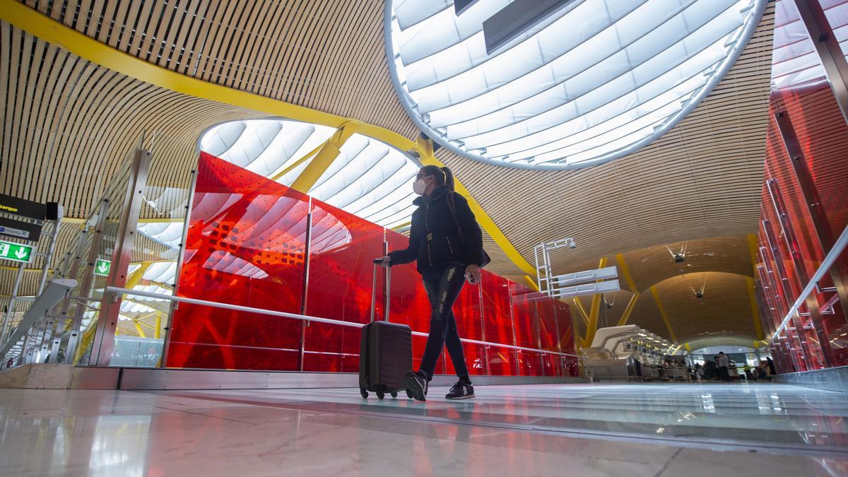 Archivo - Una pasajera desplaza su maleta por las instalaciones de la T4 del Aeropuerto Adolfo Suárez Madrid-Barajas, en Madrid (España), a 26 de marzo de 2021.