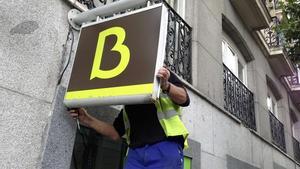Un treballador col·loca el logo de Bankia en una oficina de l’entitat a Madrid.