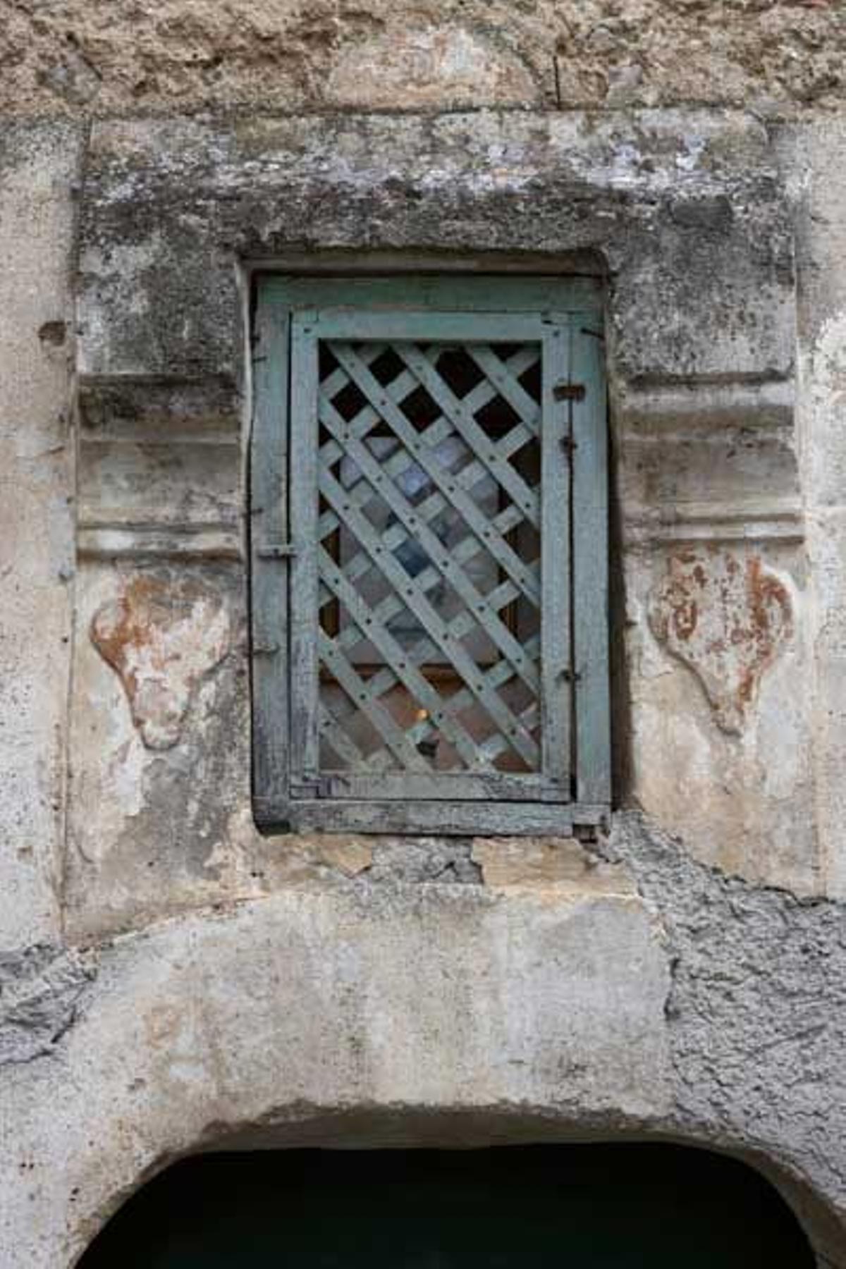 Detalle de una reja realizada en forja en una ventana en un edificio de piedra en Positano.