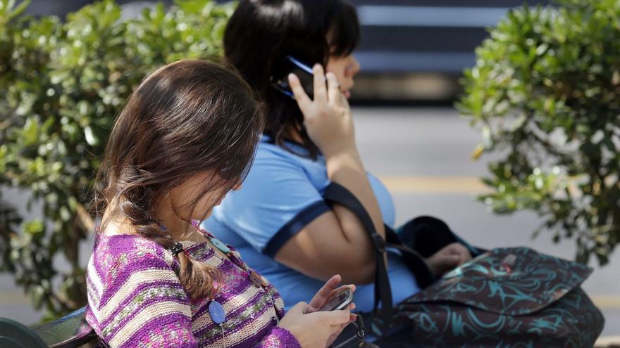 Dos mujeres usan sus móviles en la calle.