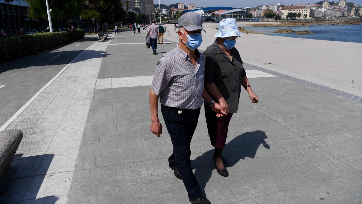 Una pareja de ancianos pasea con mascarilla por A Coruña.