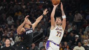 Los Angeles Lakers guard Luka Doncic (77)looks to shoot over Phoenix Suns guard Devin Booker, front left, during the first half of an NBA basketball game, Sunday, Dec. 14, 2025, in Phoenix. (AP Photo/Rick Scuteri)