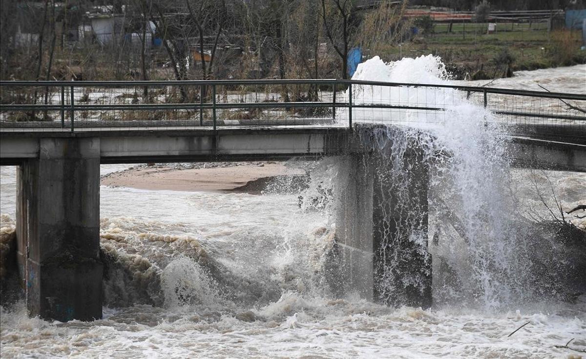 El agua que sale de una tubería rota sobre un puente dañado cae al río Ter, en Anglés, cerca de Girona, durante la tormenta Gloria.