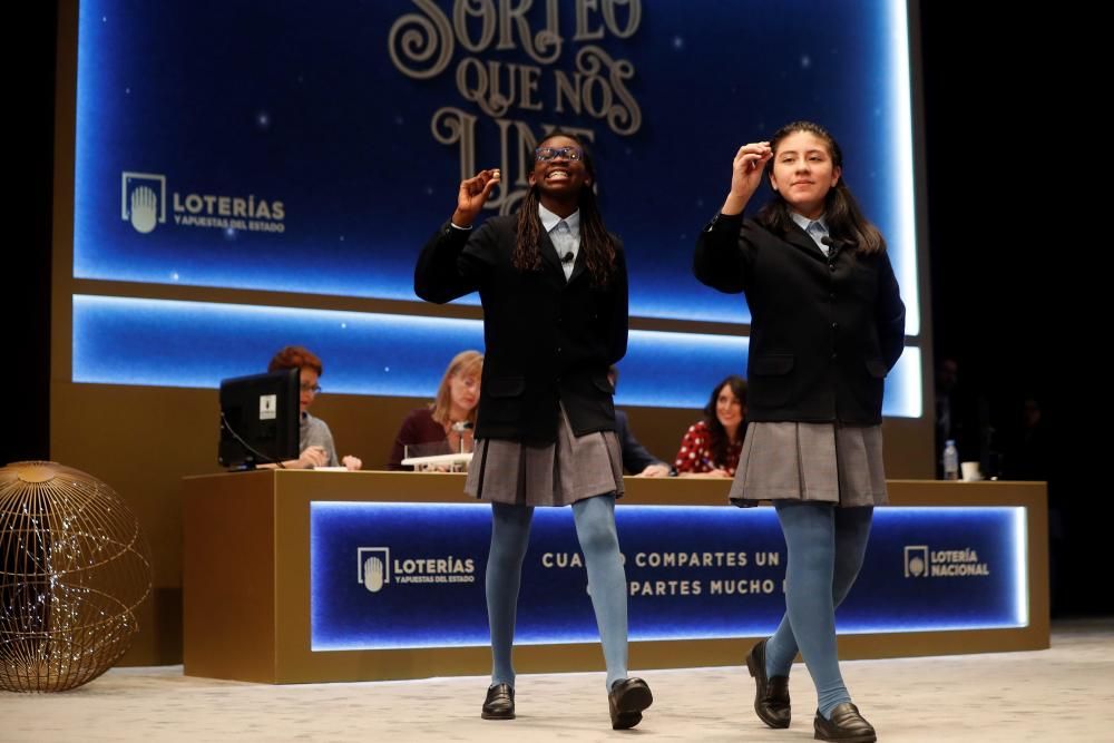 Las niñas del colegio de San ildefonso Yanisse Alexandra Soto (d) y Elisabeth Obarisiagbon Iyamu muestran las bolas con el número 74.770 que ha sido agraciado con uno de los quintos premios.