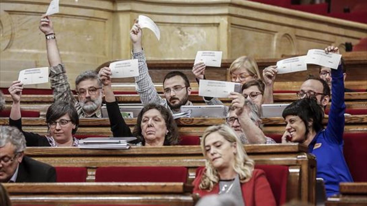 Los diputados de la CUP exhiben papeletas del eventual referéndum, ayer, en el debate del Parlament sobre los presupuestos.