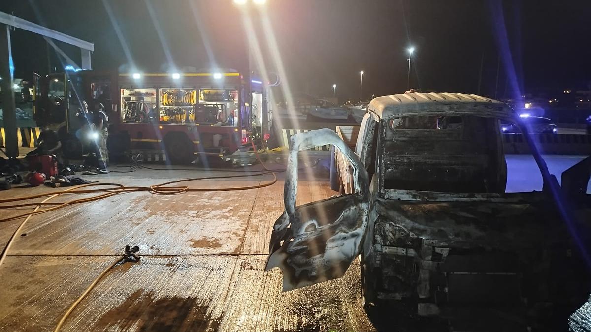 El camión incendiado y los bomberos, al fondo.