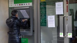 Una persona mayor utiliza un cajero de Unicaja durante las protestas por el ERE en Zamora.