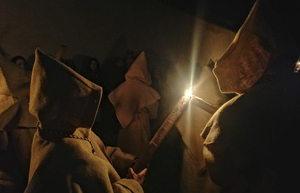 Un hermano prende la tea de otro cofrade durante el recorrido de la procesión. | M. J. C.