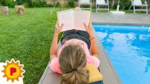 Una adolescente, leyendo un libro en la piscina.