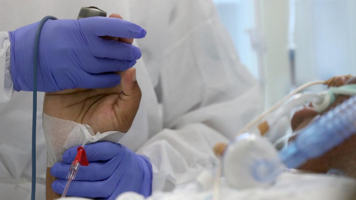 Un sanitario sostiene la mano a un paciente de covid-19 en un hospital de Bruselas, este viernes.