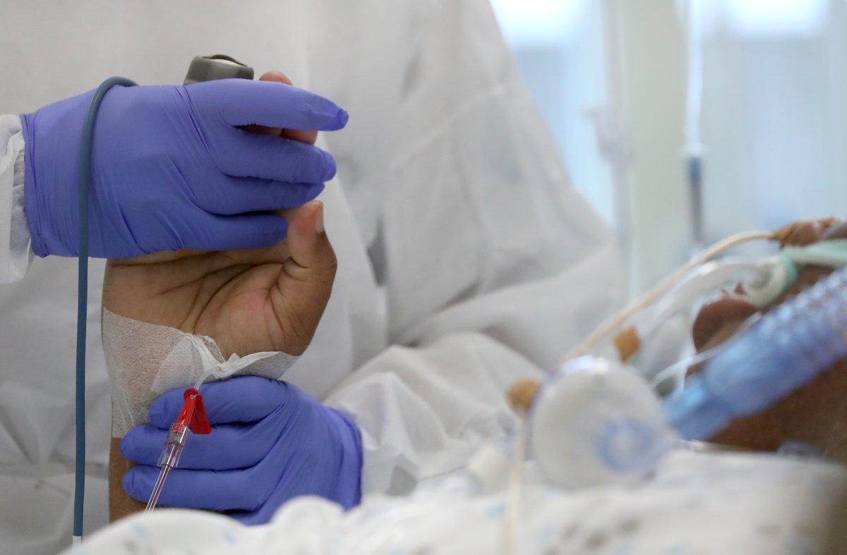 A member of the medical personnel holds a hand of a patient suffering from the coronavirus disease (COVID-19) who is treated at the CHIREC Delta hospital, in Brussels, Belgium October 23, 2020. REUTERS/Yves Herman