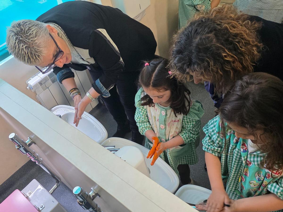 La consejera de Salud, Concepción Saavedra, y la consejera de Educación, Eva Ledo, ayudando a lavarse las manos a dos alumnas del centro.