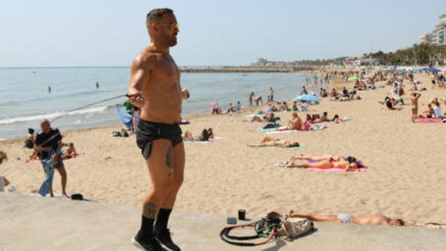 Una platja de Sitges amb un home fent exercici en primer pla