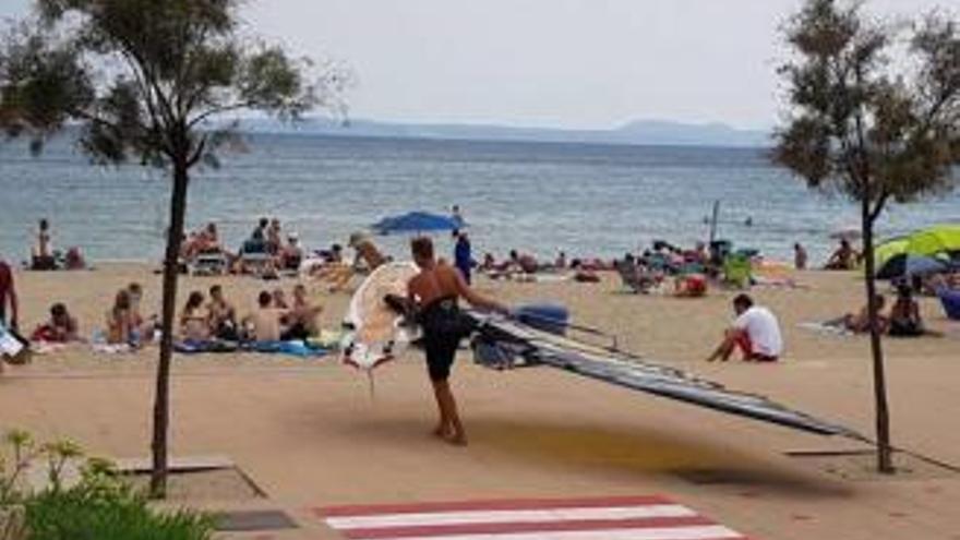 Un esportista, passant per la platja amb la vela