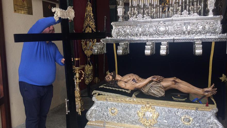 Un miembro de la Hermandad del Santo Sepulcro limpia la cruz guía que utilizarán el Viernes.