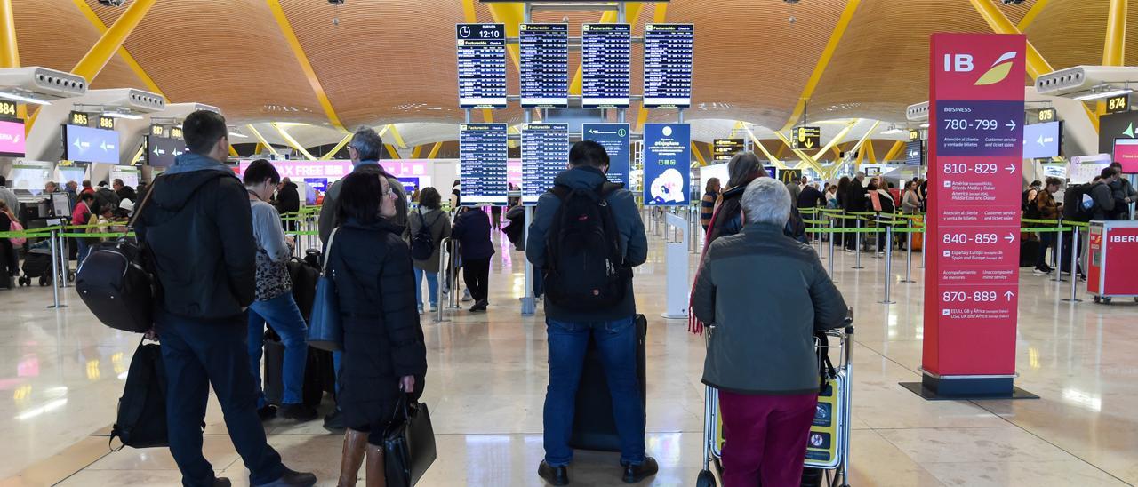 Archivo - Varias personas esperan para embarcar y facturar en la zona de salidas de la Terminal 4 del Aeropuerto Madrid-Barajas Adolfo Suárez