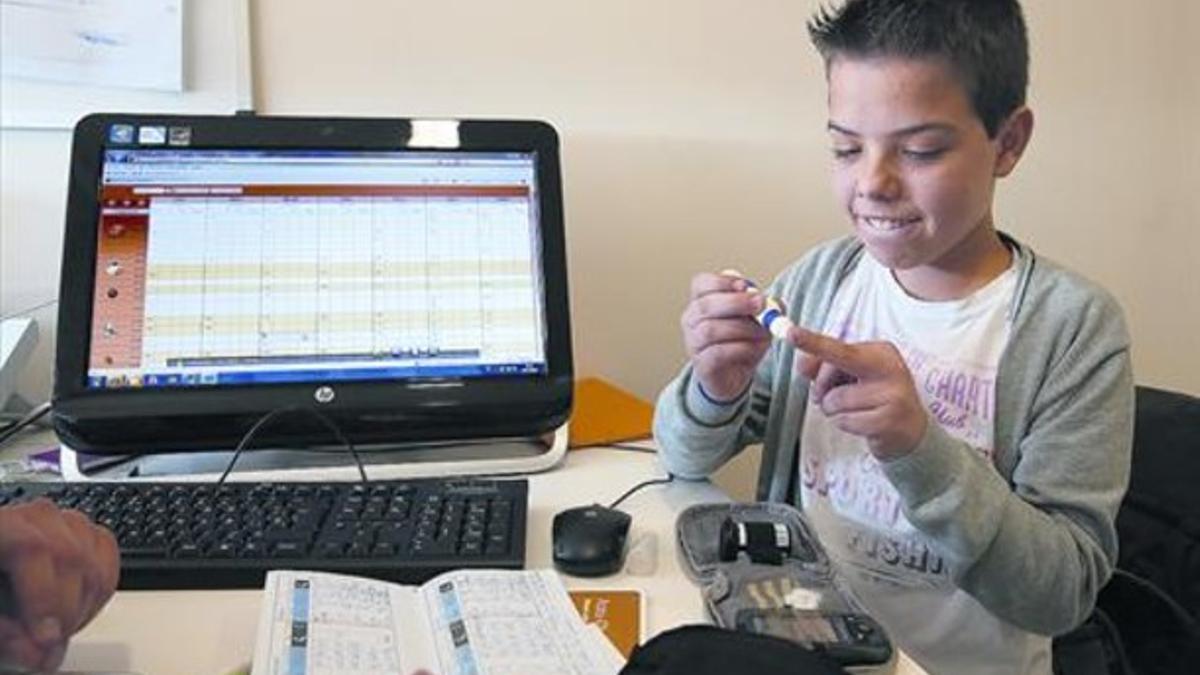 Un niño, paciente del Hospital de Sant Joan de Déu, aprende a utilizar el aparato con que se inyecta insulina.