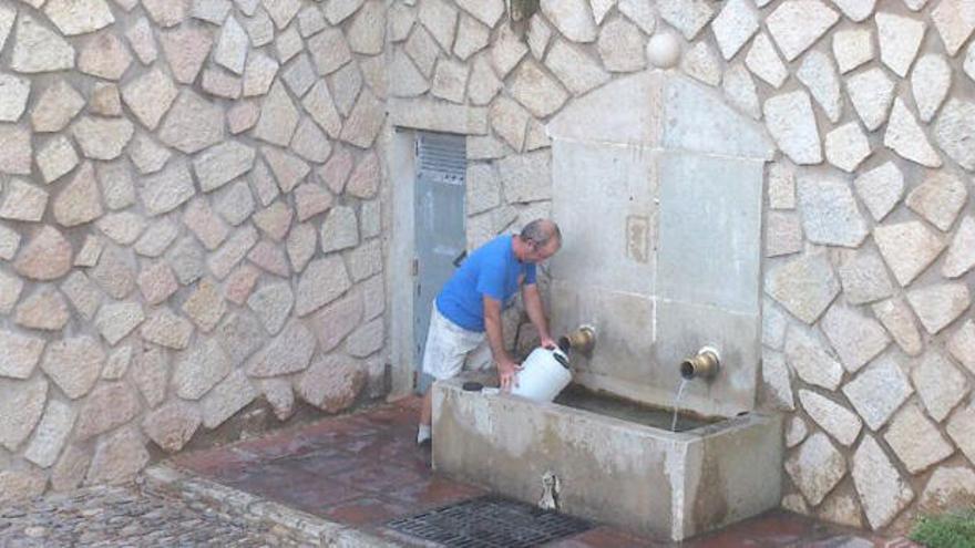 Un vecino del Valle de Abdalajís llena un bidón de agua en una fuente pública.